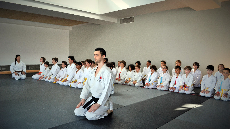 Discipline et tradition au dojo : la section karaté enfant Karaté enfants : Pour le salut, alignés à genoux sur le tatami pour le salut traditionnel sous la direction de leur instructeur.